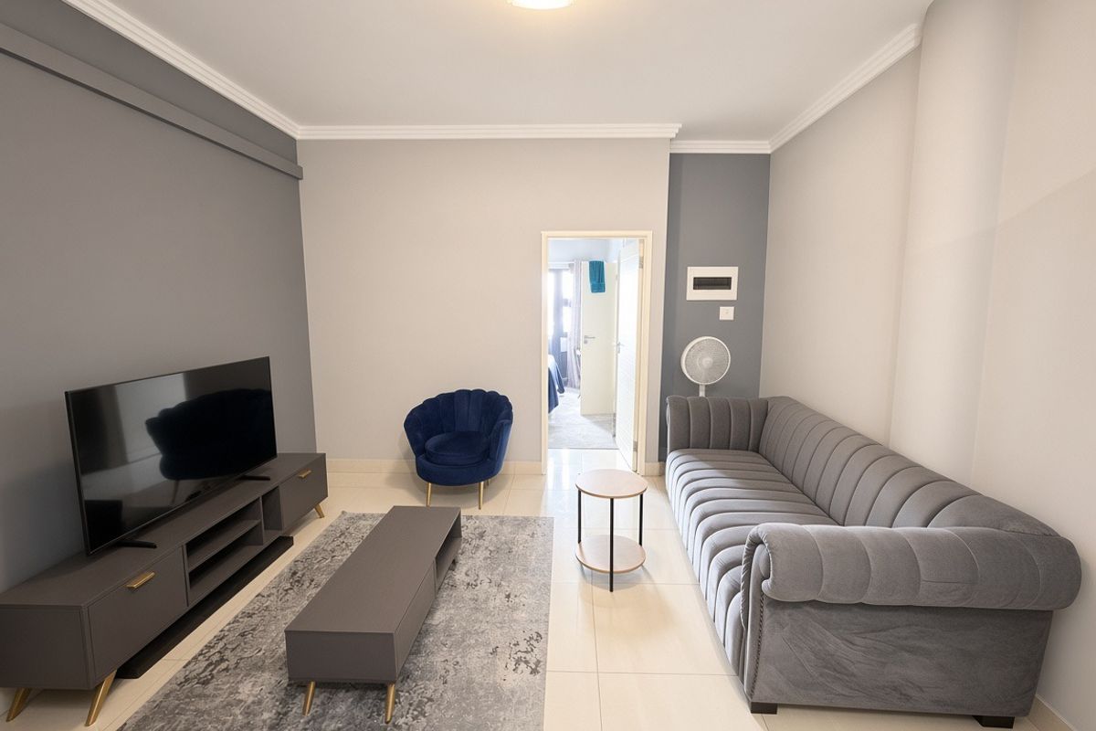 A well-maintained living room featuring neutral grey walls, tiled flooring, and crown molding, providing a clean and modern aesthetic.