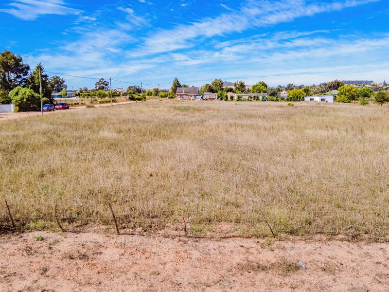 A wide-angle view of a vacant residential plot featuring natural grass cover and perimeter wire fencing.