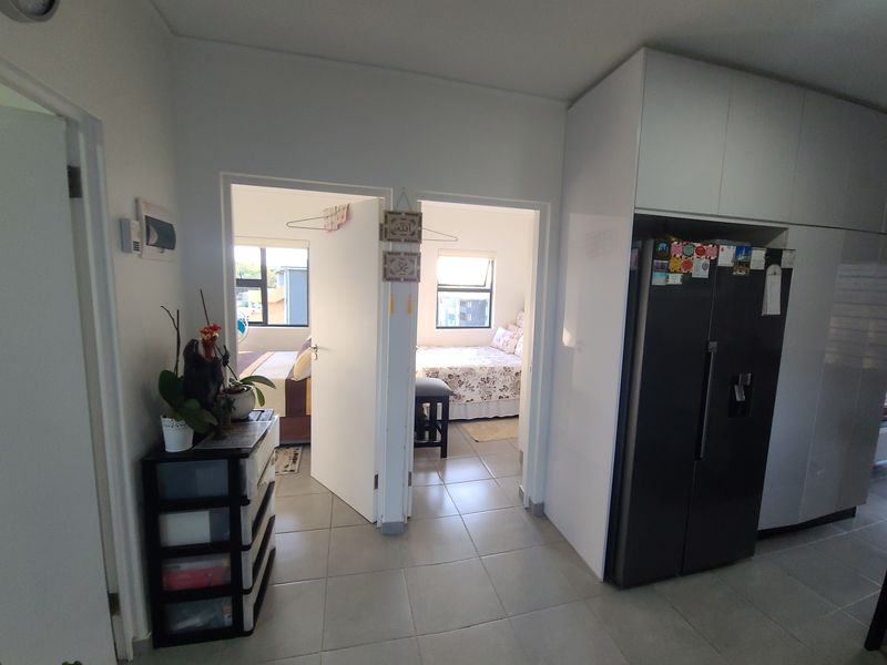 A functional hallway area featuring tiled flooring and built-in cabinetry, providing access to adjacent bedrooms.