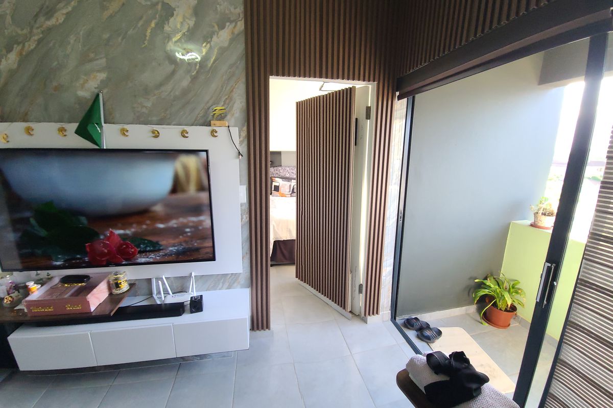 Modern living area featuring stylish marble-effect wall cladding, timber slat paneling, and large sliding glass doors leading to an outdoor balcony space.