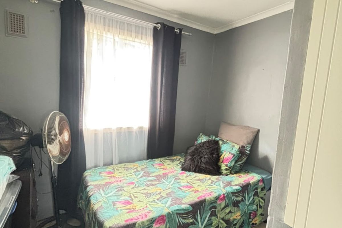 A compact bedroom featuring neutral wall paint and tiled flooring, providing a functional space with natural light from the window.