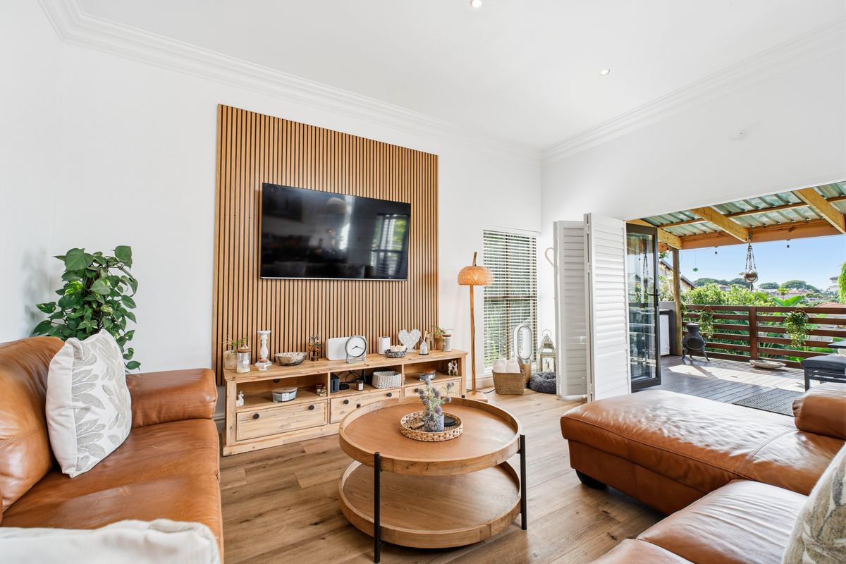 Bright and modern living room featuring a timber slat feature wall, timber flooring, and seamless flow to an outdoor patio through bi-fold doors.