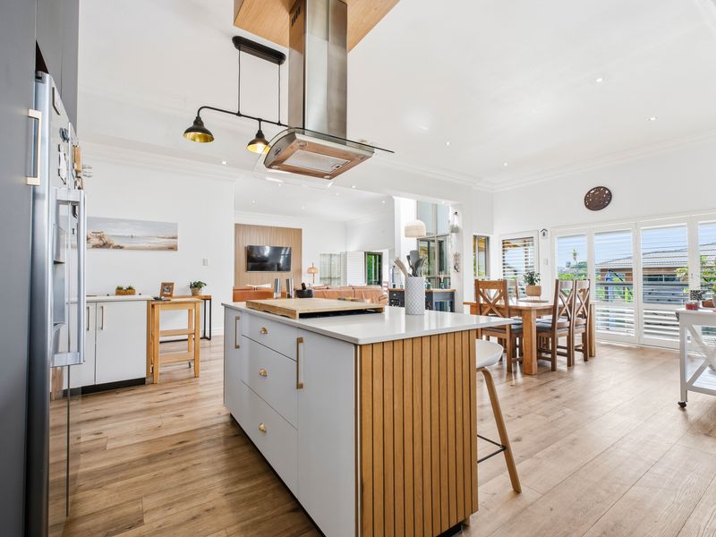 Spacious open-plan kitchen and dining area featuring a modern island, timber-look flooring, and seamless flow to the outdoor living space.