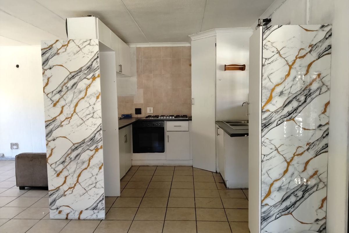 A functional kitchen featuring built-in oven, gas hob, double sink, and tiled splashback, offering a blank canvas for modern renovation and aesthetic updates.