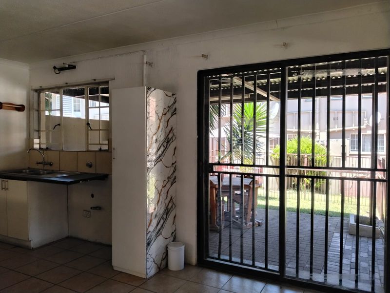 Open plan kitchen area featuring tiled floors and a sliding door leading to a paved patio and garden space.