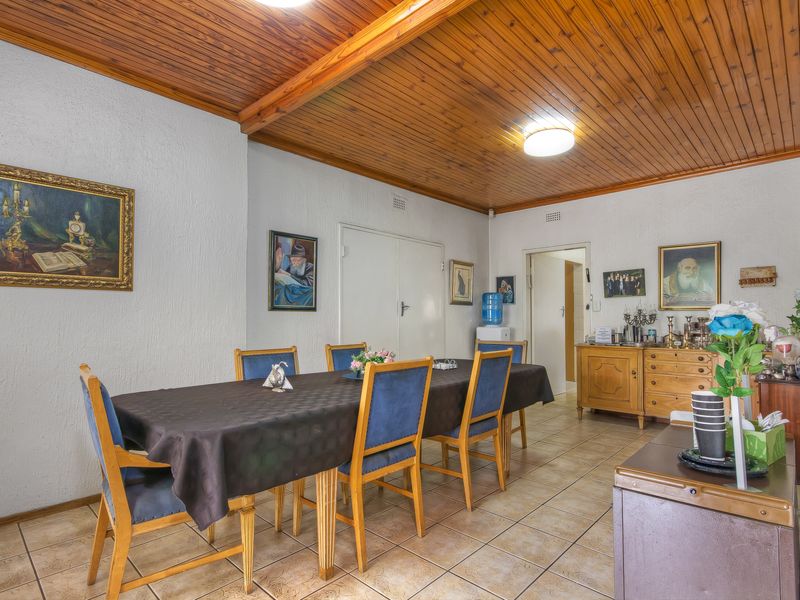 Dining room featuring a classic timber tongue and groove ceiling with exposed beams and neutral ceramic floor tiles.