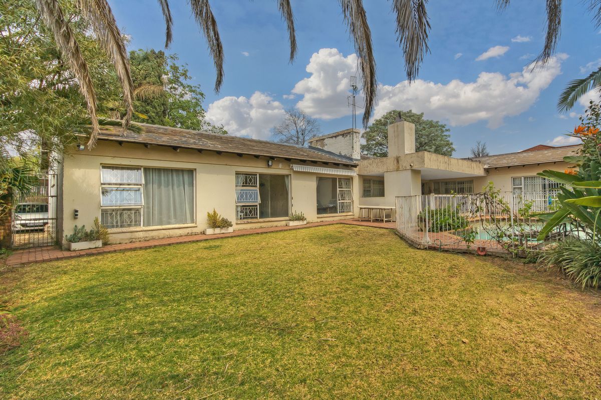 Rear view of the property featuring a swimming pool, paved patio area, and established garden with direct access to the living spaces.