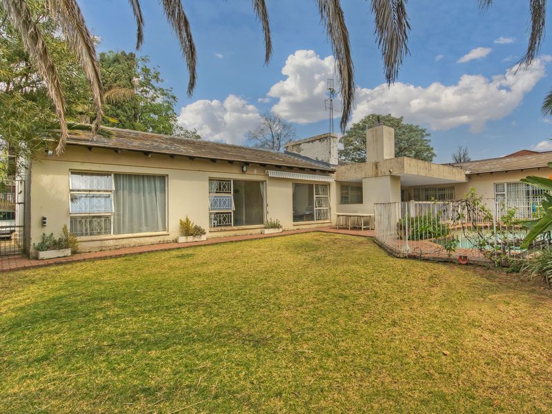 Rear view of the property featuring a swimming pool, paved patio area, and established garden with direct access to the living spaces.
