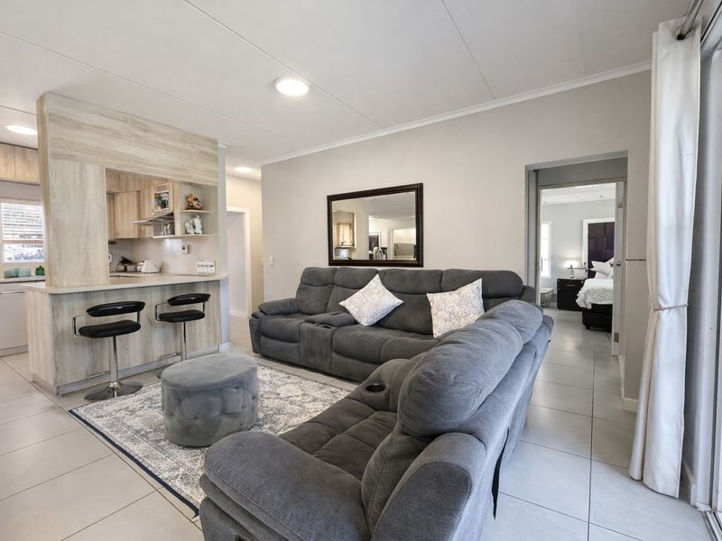 Open-plan living area featuring tiled floors, a breakfast bar with built-in cabinetry, and direct access to an outdoor space via sliding glass doors.