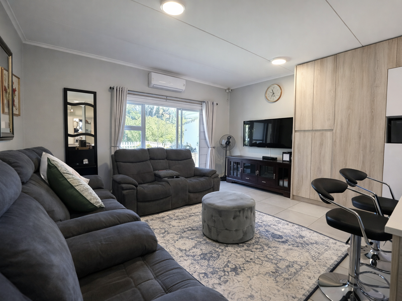 A well-maintained open-plan living area featuring tiled floors, built-in cabinetry, and a sliding glass door providing natural light.