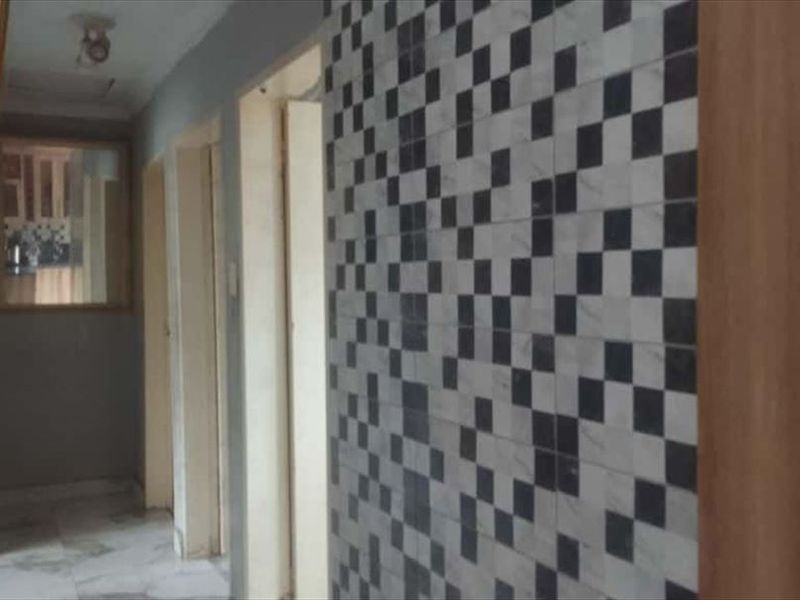 A functional hallway featuring tiled flooring and a distinctive checkered feature wall, providing access to multiple rooms within the townhouse.