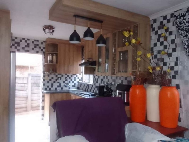 A functional kitchen featuring wood-finish cabinetry, a tiled backsplash, and integrated cooking appliances, with direct access to an outdoor area.