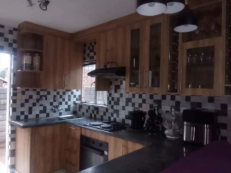 A functional kitchen featuring wood-look cabinetry, dark laminate countertops, a built-in oven and hob, and a distinctive checkered tile backsplash.