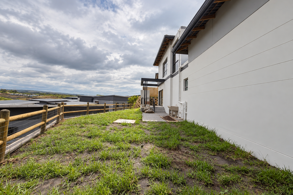 Rear exterior view of the property featuring a concrete patio, external utility sink, and a timber post and wire fence overlooking the surrounding area.