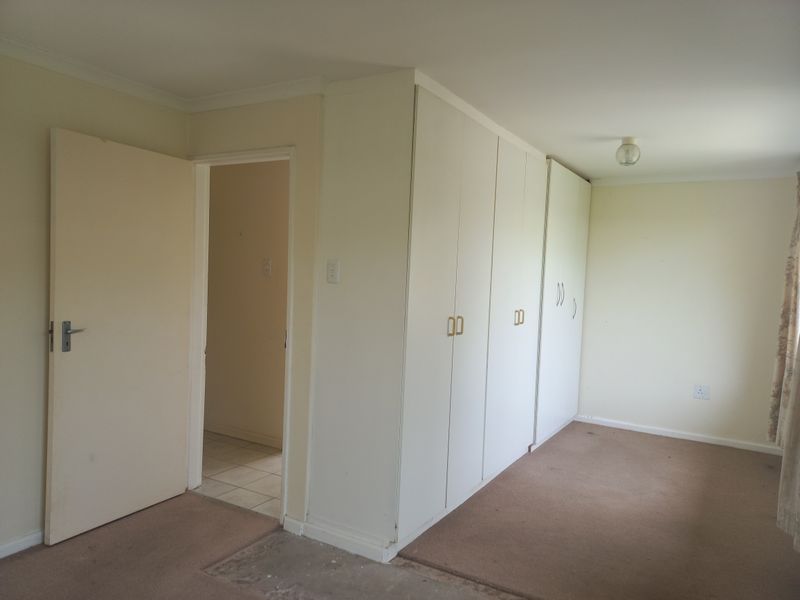 An empty bedroom featuring built-in cupboards, neutral walls, and carpet flooring, offering a blank canvas for potential updates and interior design.