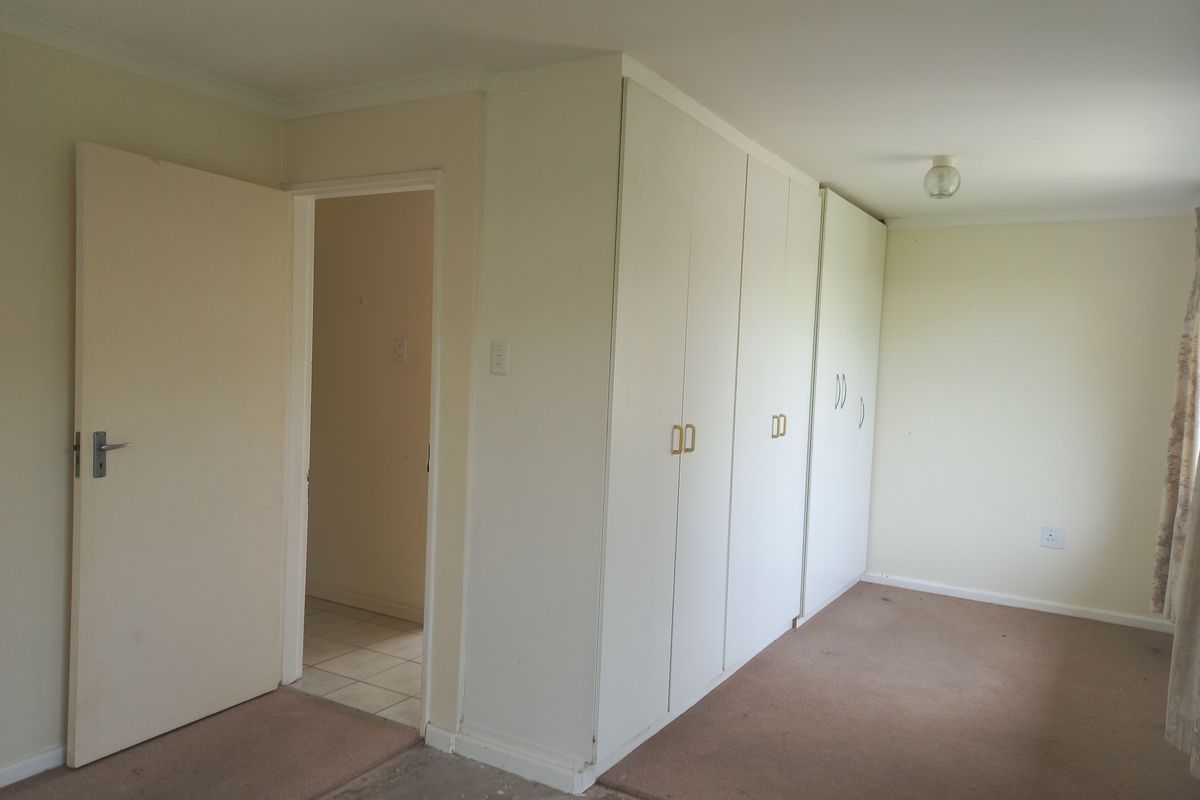 An empty bedroom featuring built-in cupboards, neutral walls, and carpet flooring, offering a blank canvas for potential updates and interior design.