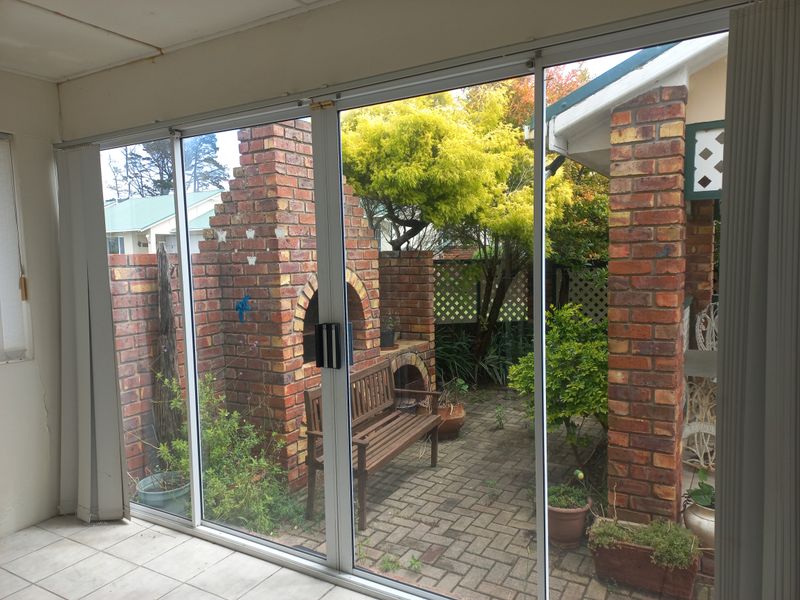 Enclosed patio area featuring tiled flooring and sliding glass doors opening onto a private courtyard with a built-in brick fireplace.