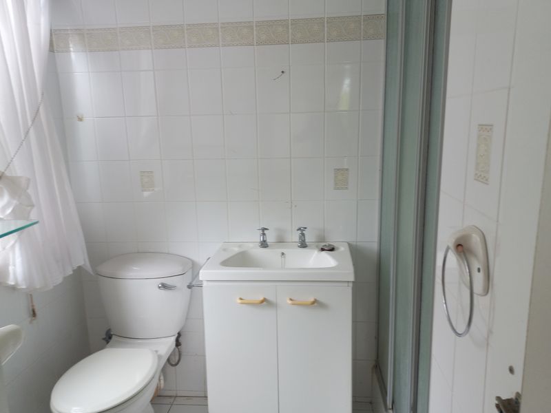A functional bathroom featuring a vanity cabinet with basin, toilet, and a shower enclosure with tiled walls.
