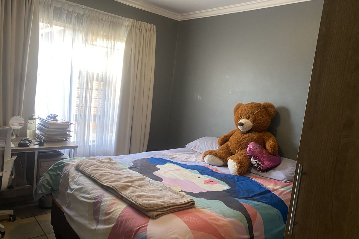A functional bedroom featuring tiled flooring, a built-in cupboard, and natural light from the window.