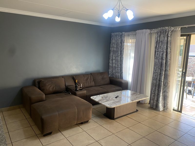 A living room featuring tiled flooring, a ceiling light fixture, and a sliding glass door providing access to the outdoor area.