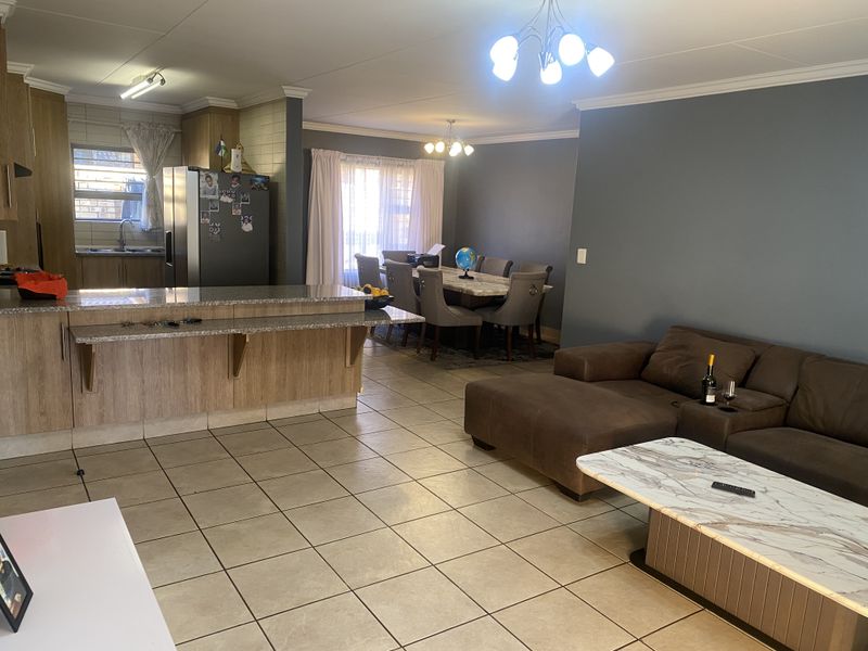 Spacious open-plan living area featuring a kitchen with granite countertops, a breakfast bar, and tiled flooring throughout the dining and lounge spaces.
