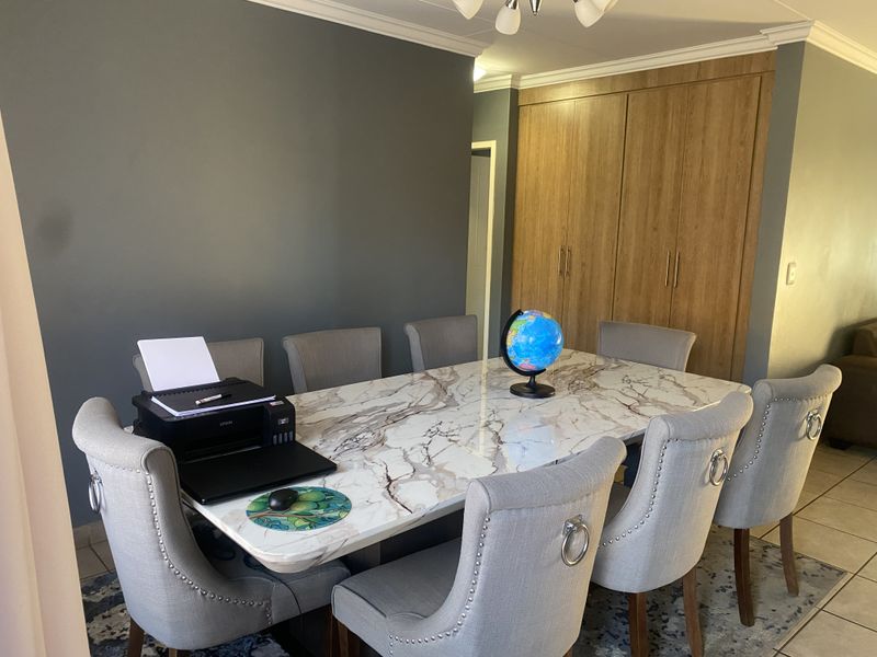 A well-maintained dining area featuring built-in wooden cabinetry, crown molding, and tiled flooring, providing a functional space for meals and gatherings.