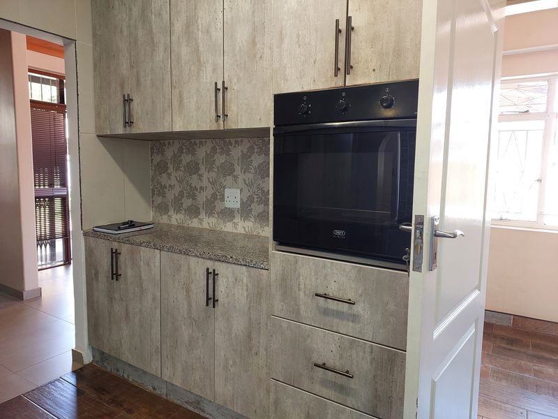 A functional kitchen area featuring built-in cabinetry, a granite countertop, and a modern integrated oven with a decorative tiled backsplash.