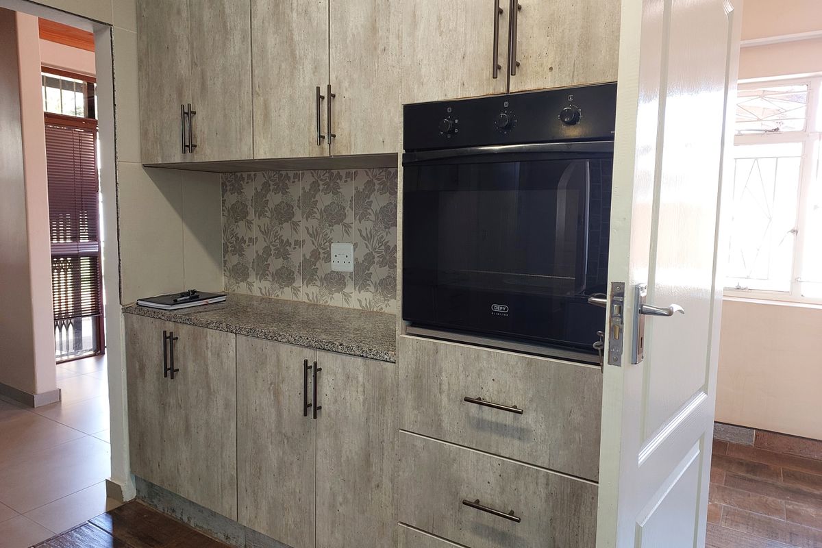 A functional kitchen area featuring built-in cabinetry, a granite countertop, and a modern integrated oven with a decorative tiled backsplash.