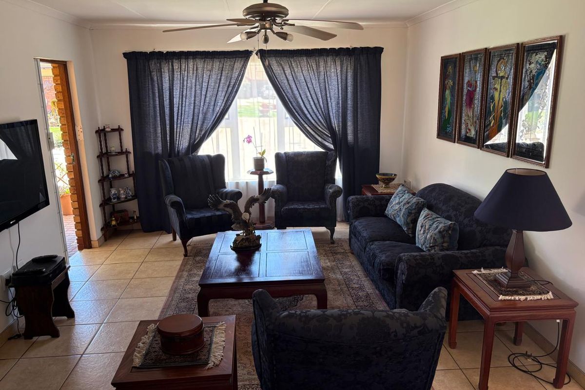 A comfortable living room featuring tiled flooring, a ceiling fan, and direct access to an outdoor area through a sliding door.