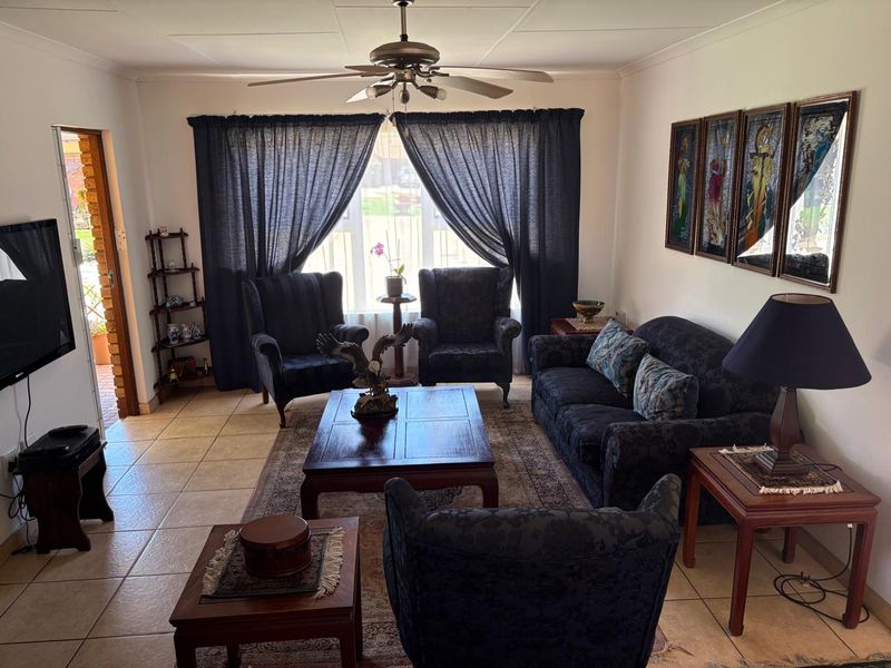 A comfortable living room featuring tiled flooring, a ceiling fan, and direct access to an outdoor area through a sliding door.