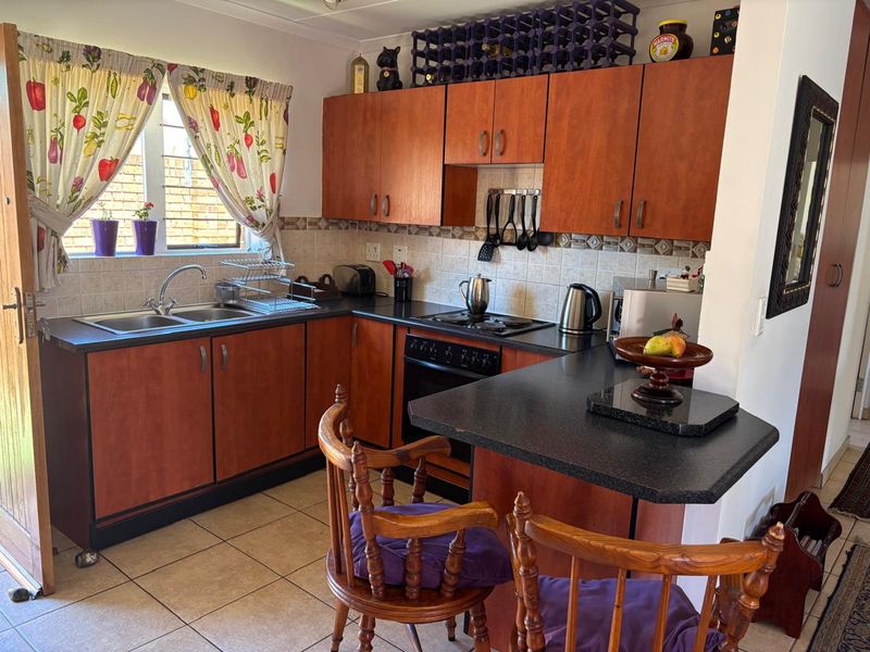 A functional kitchen featuring wood-look cabinetry, dark laminate countertops, a breakfast bar, and integrated cooking appliances with a tiled backsplash.