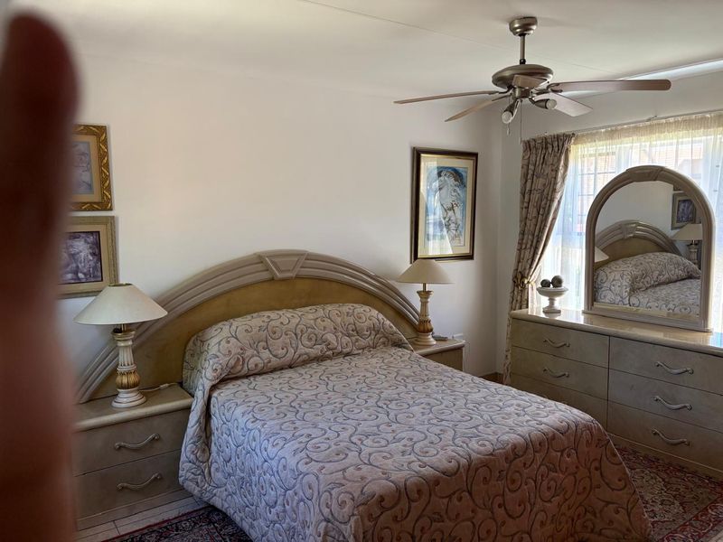 A bedroom featuring a ceiling fan and window treatments, offering a functional space with potential for modern updates.