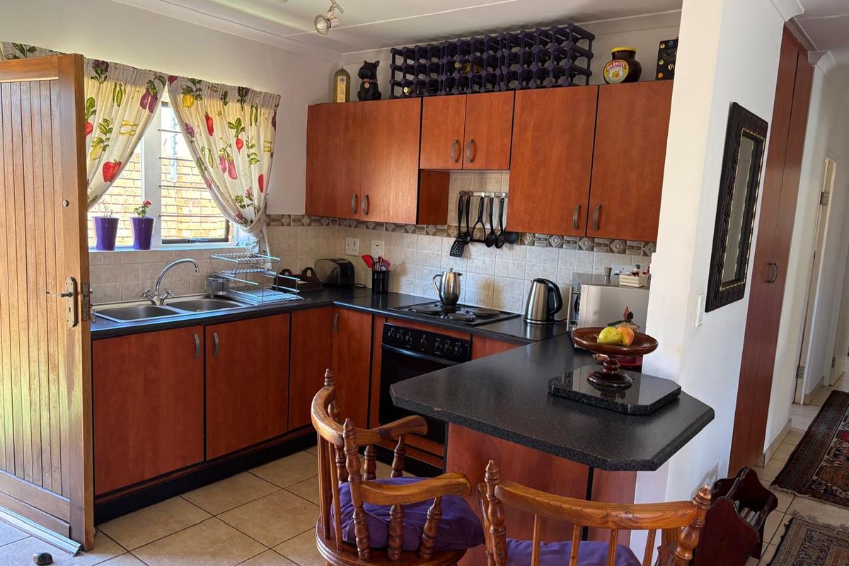 A functional kitchen featuring wood-look cabinetry, dark laminate countertops, a breakfast bar, and tiled flooring, offering a practical layout for daily meal preparation.