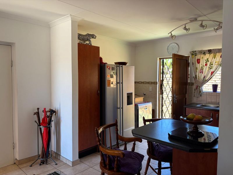 A functional kitchen area featuring tiled backsplashes, built-in cabinetry, and direct access to the exterior through a security gate.