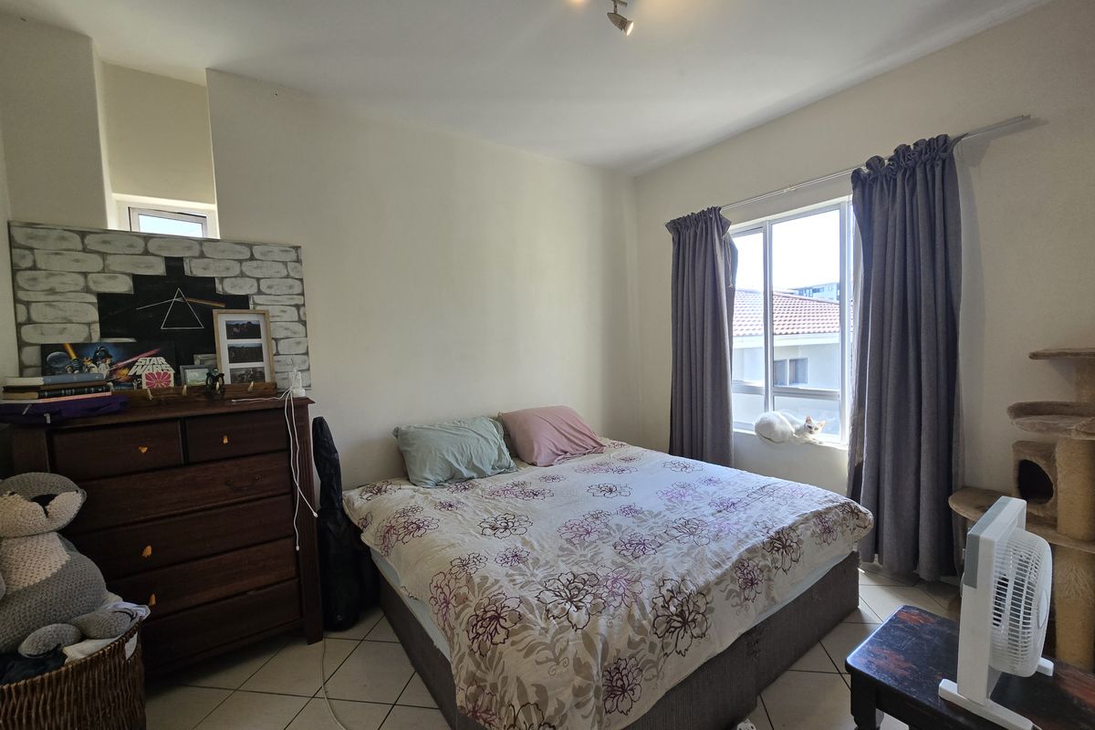 A bedroom featuring tiled flooring and a window with curtain tracks, providing natural light and a functional living space.