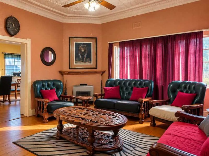 A spacious living room featuring original ornate ceilings, hardwood flooring, and a fireplace, offering a classic character aesthetic with potential for modern updates.
