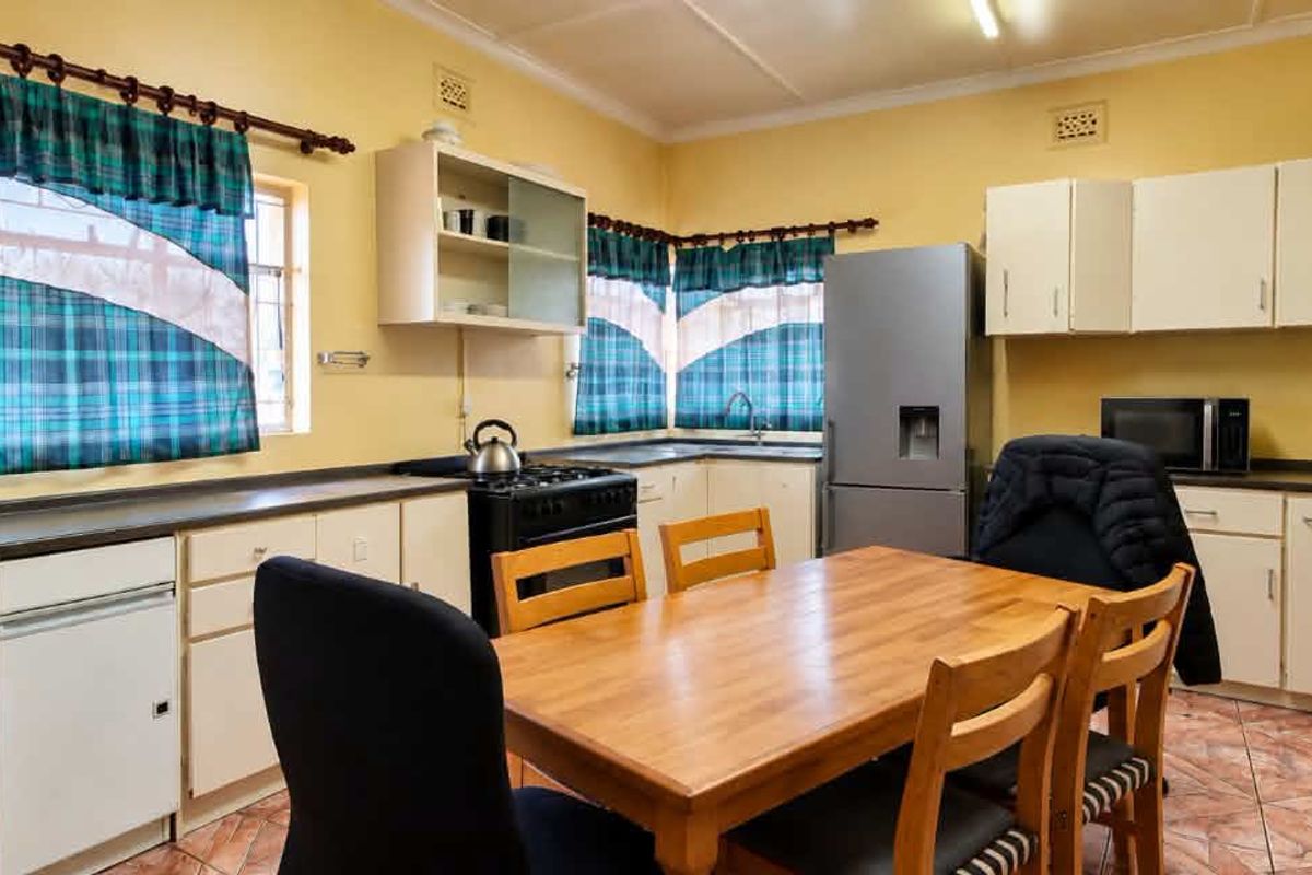 A functional kitchen featuring ample built-in cabinetry, laminate countertops, and tiled flooring, offering a practical layout with space for a dining area.