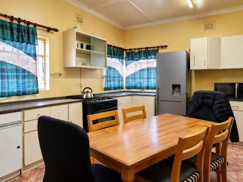 A functional kitchen featuring ample built-in cabinetry, laminate countertops, and tiled flooring, offering a practical layout with space for a dining area.