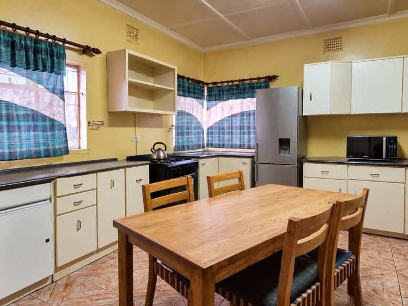 A functional kitchen featuring ample built-in cabinetry, laminate countertops, and tiled flooring, offering a practical layout with potential for modern updates.