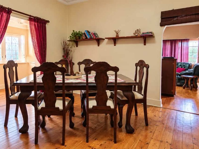 A dining room featuring warm timber flooring and a classic arched doorway leading to an adjacent living space.