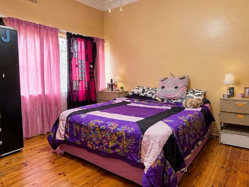 A bedroom featuring warm timber flooring and classic cornice detailing, offering a comfortable and functional living space.