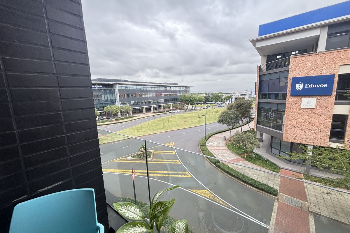 An elevated urban view from a balcony overlooking a street intersection and surrounding commercial buildings.
