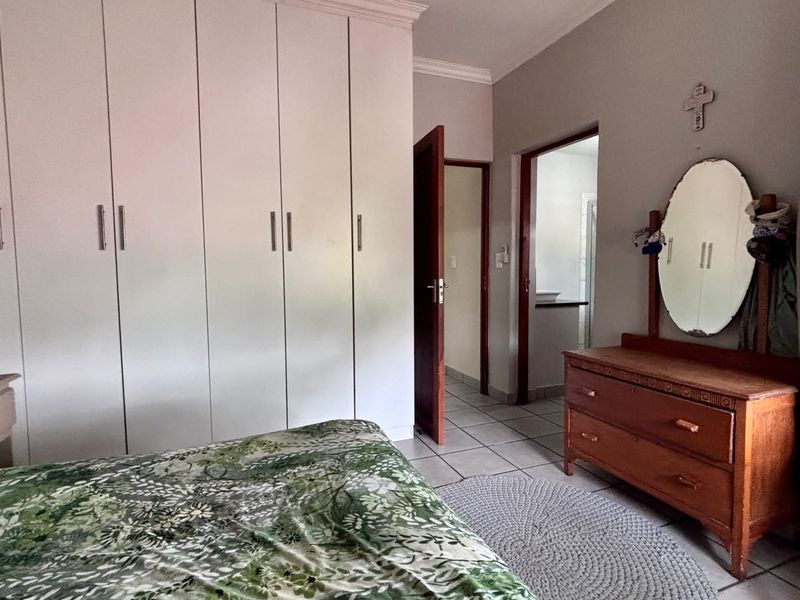 A bedroom featuring built-in cupboards, tiled flooring, and direct access to an adjoining bathroom.