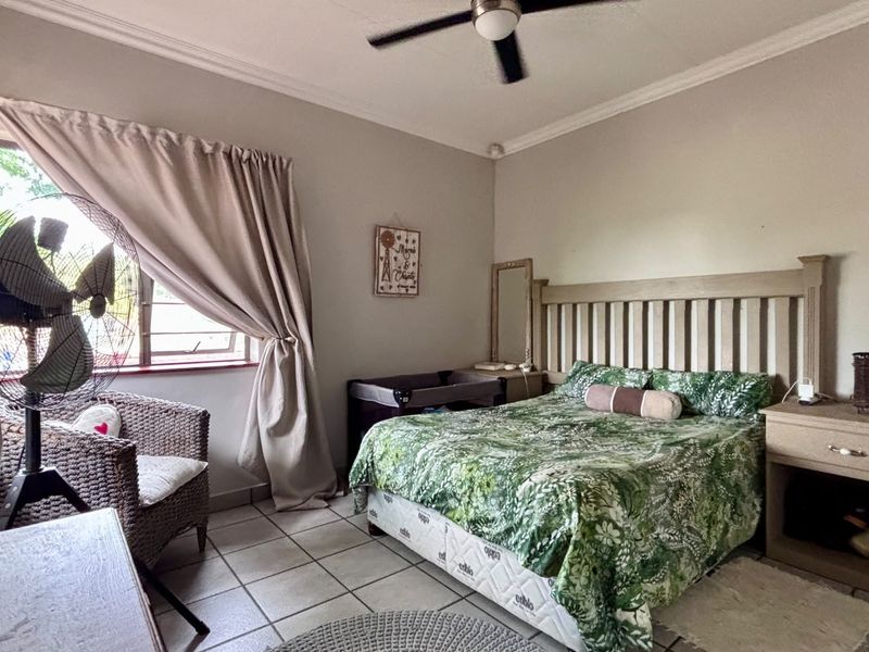 A bedroom featuring tiled flooring, a ceiling fan, and neutral wall finishes.