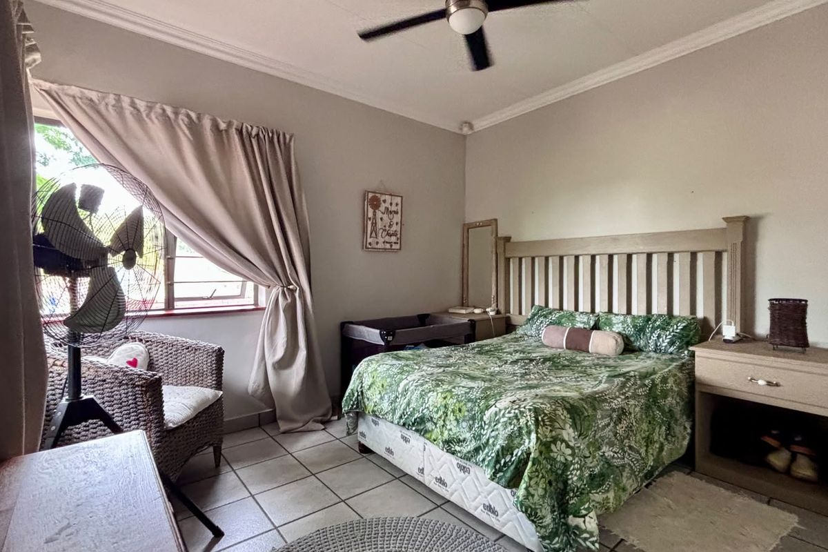 A bedroom featuring tiled flooring, a ceiling fan, and neutral wall finishes.