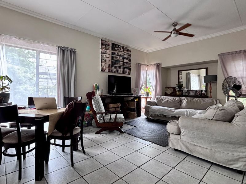 Spacious open-plan living and dining area featuring tiled flooring, a ceiling fan, and a built-in alcove, offering a versatile layout for family living.