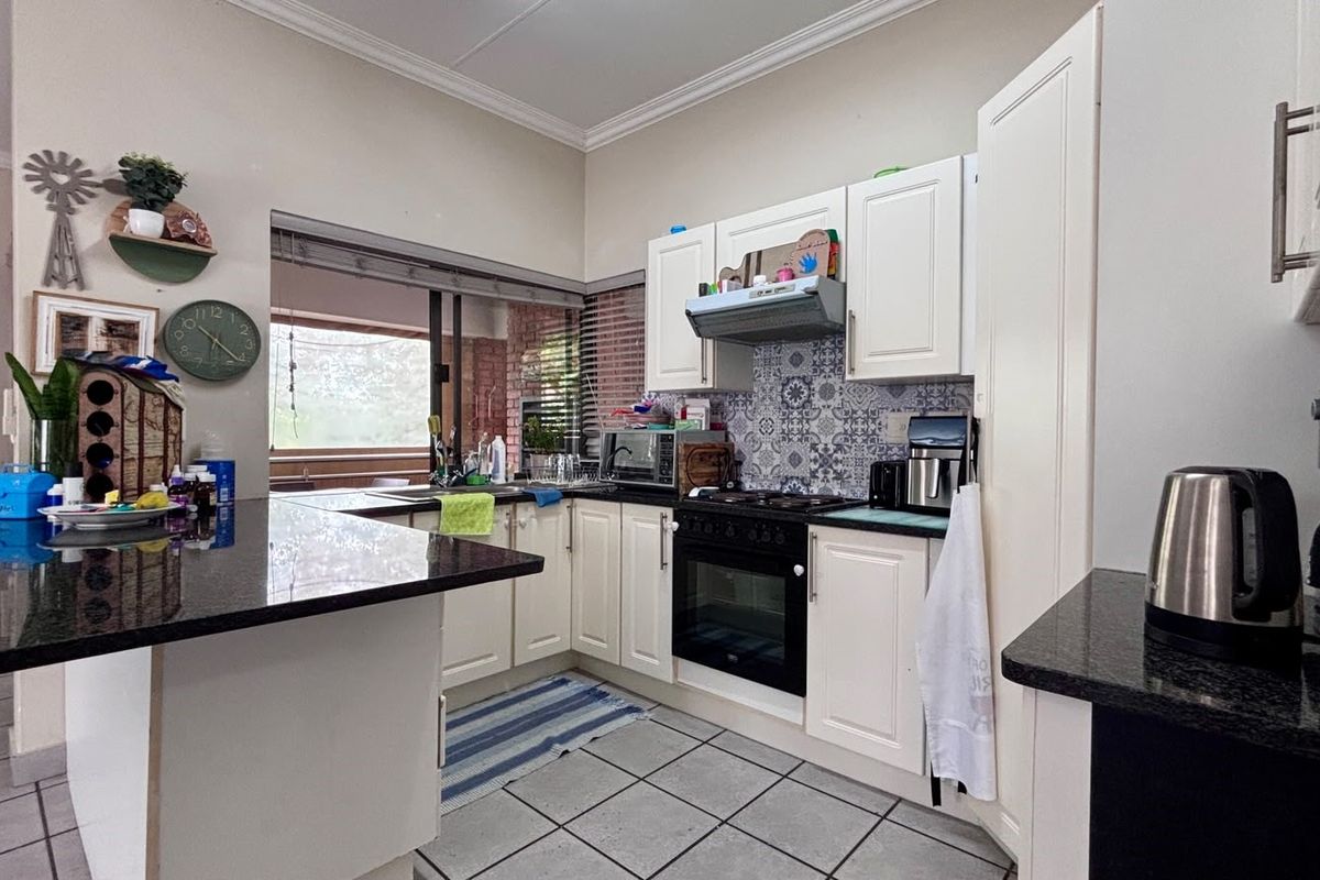 Functional kitchen featuring granite countertops, built-in oven with gas hob, patterned tile backsplash, and ample cabinetry, offering a practical layout for daily cooking.