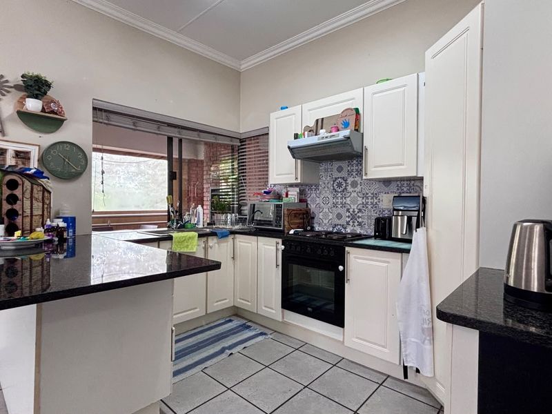 Functional kitchen featuring granite countertops, built-in oven with gas hob, patterned tile backsplash, and ample cabinetry, offering a practical layout for daily cooking.