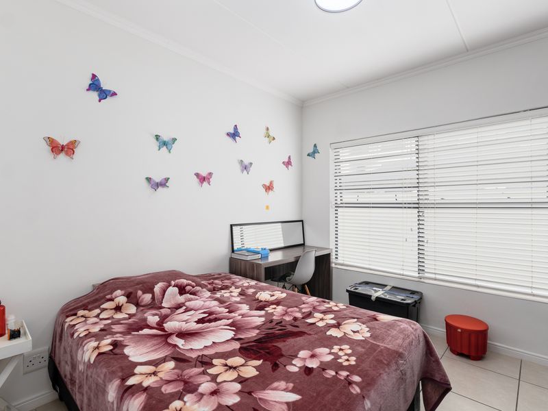 A bedroom featuring tiled flooring, coved ceilings, and venetian blinds, providing a functional space with natural light.