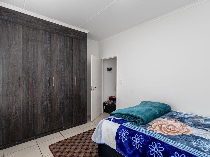 A bedroom featuring dark wood-finish built-in cupboards and neutral tiled flooring, providing ample storage space.